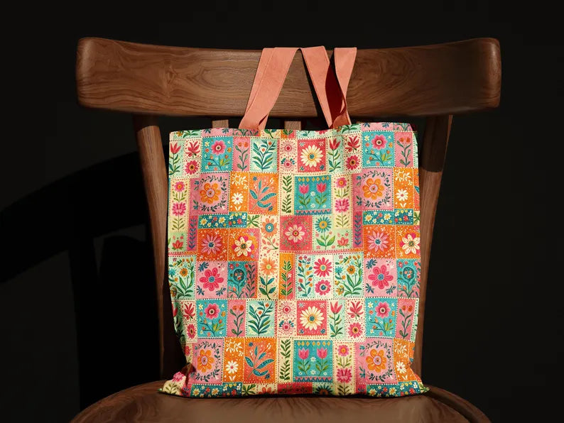 A colorful patchwork floral tote bag hanging from the back of a wooden chair against a black background.